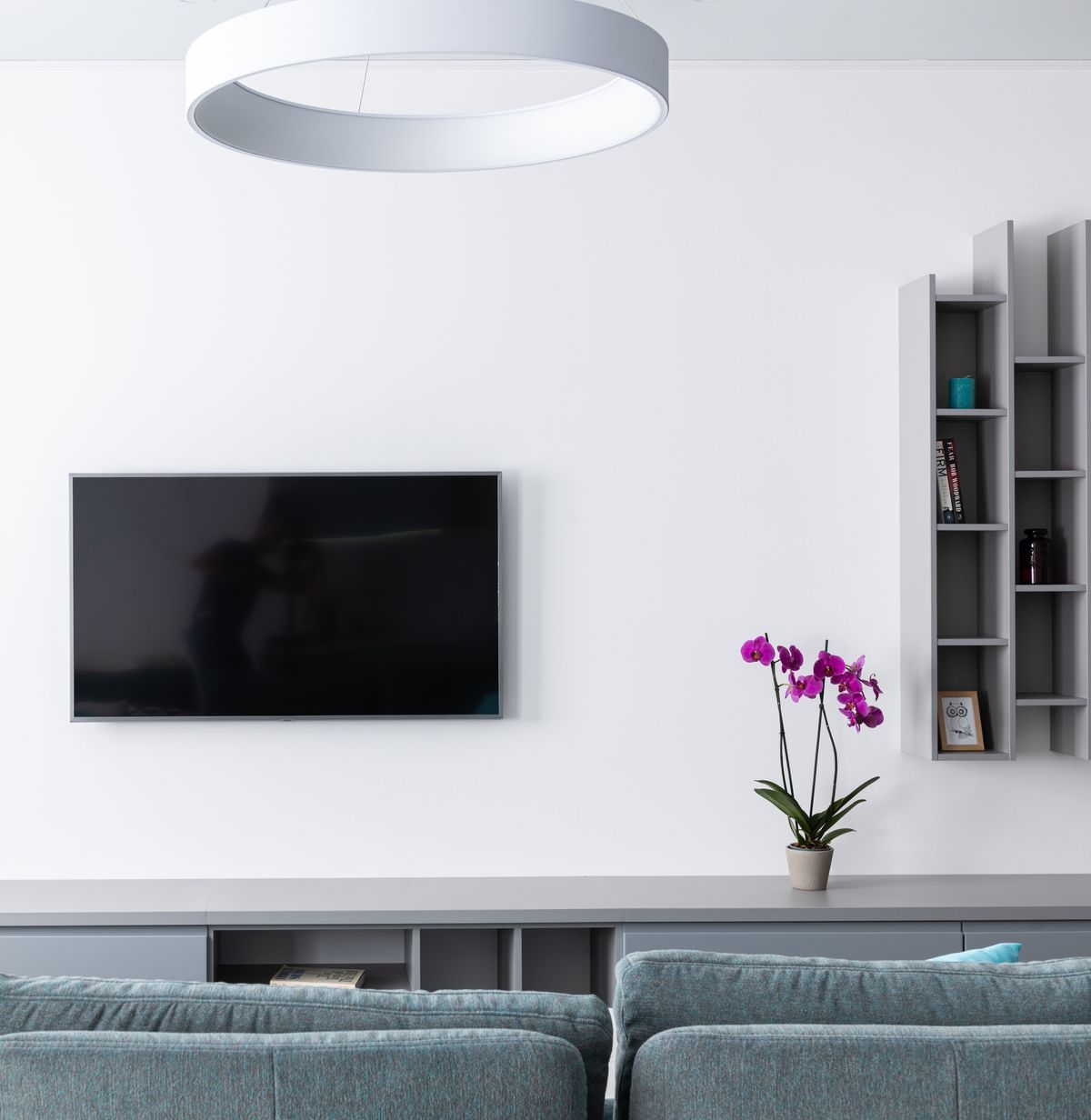 Inspiration: a wall-mounted TV in a clean white living room with gray sofas