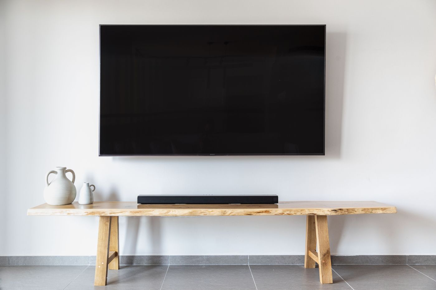 A wall-mounted TV with a soundbar fitted neatly beneath it